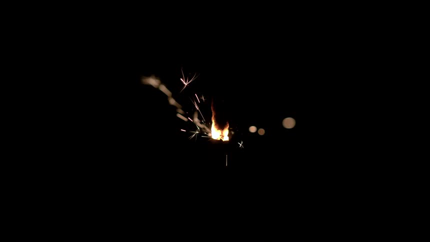 As a flame slowly burns several sparks shoot out into the darkness