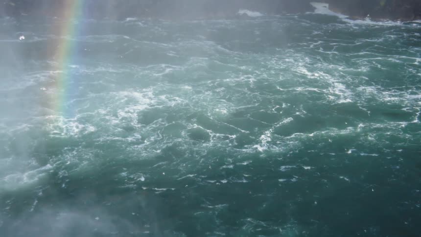 Rainbow appears over turbulent waters seen from above