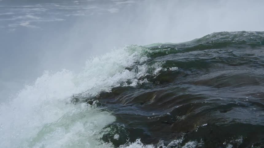 The video is a closeup shot of the incredibly powerful and turbulent water at the crest of a large waterfall likely niagara fallsit begins with an intense view of dark surging water and the cascade behind it and then the camera tilts up and down t