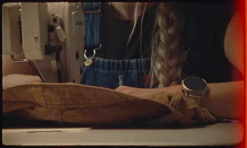 Close up of a young female tailor sewing a piece of clothing with a sewing machine in a room