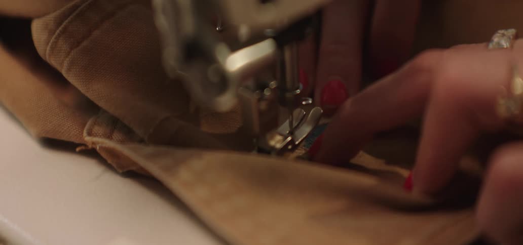 The woman is stitching clothing with a sewing machine