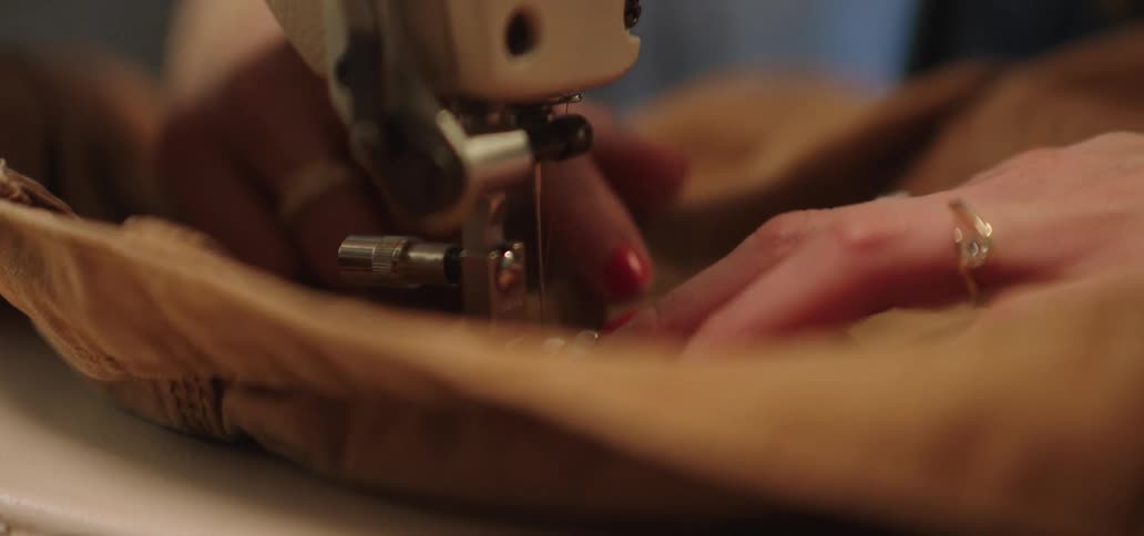 Woman sewing brown fabric on a sewing machine