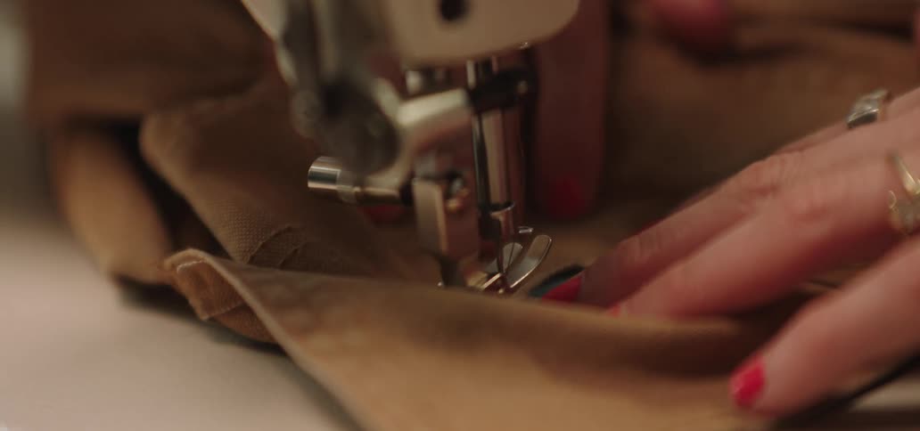 A woman sewing clothes with a sewing machine while wearing a ring