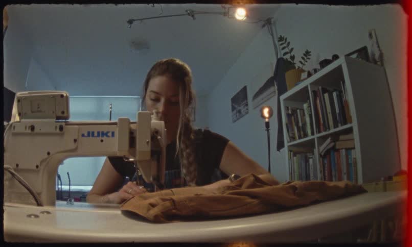 A woman is sitting in front of a sewing machine with some fabric