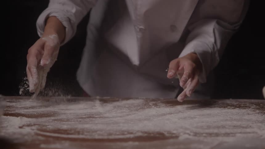 Pastry chef spreading flour on counter top and clapping his hands