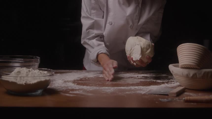 A woman preparing dough on a table covered with flour