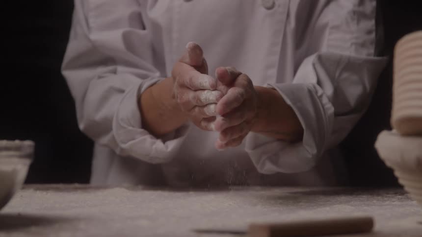 A chef grabs some flour and claps it in his hands