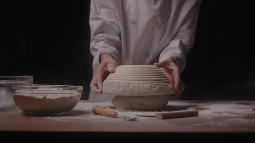 Chef shaping dough on table with flour and utensils