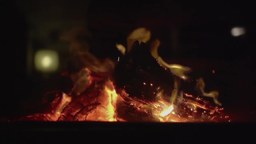 View of some burning wood giving off sparks at night