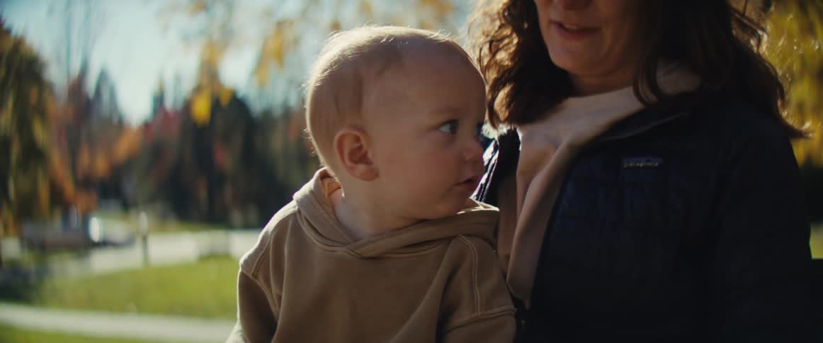 Mother holds her son on her lap on an autumn day in the park