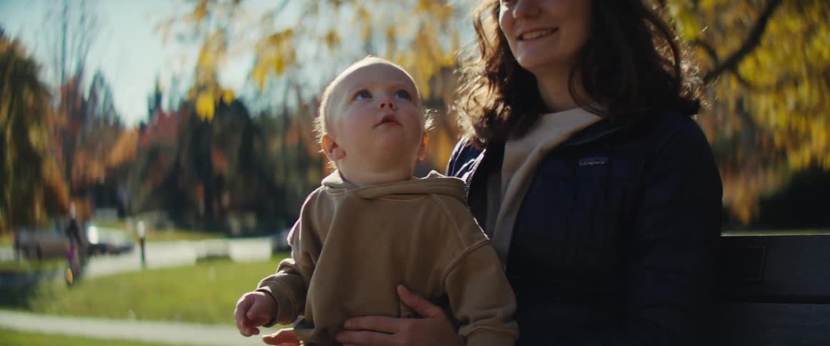 Woman and baby looking up in a park during autumn