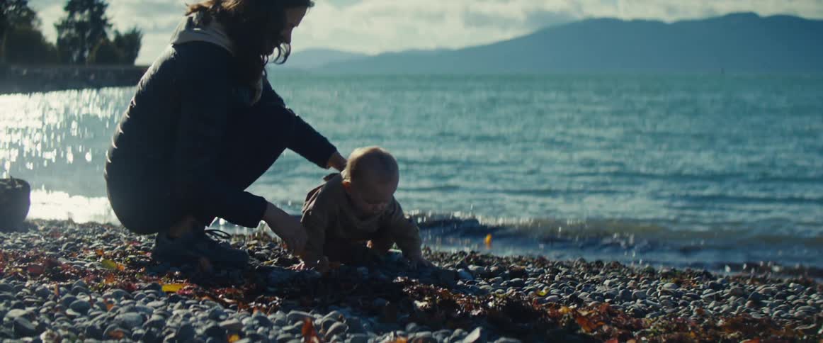 A mother and son spend time together by the shore on a sunny day