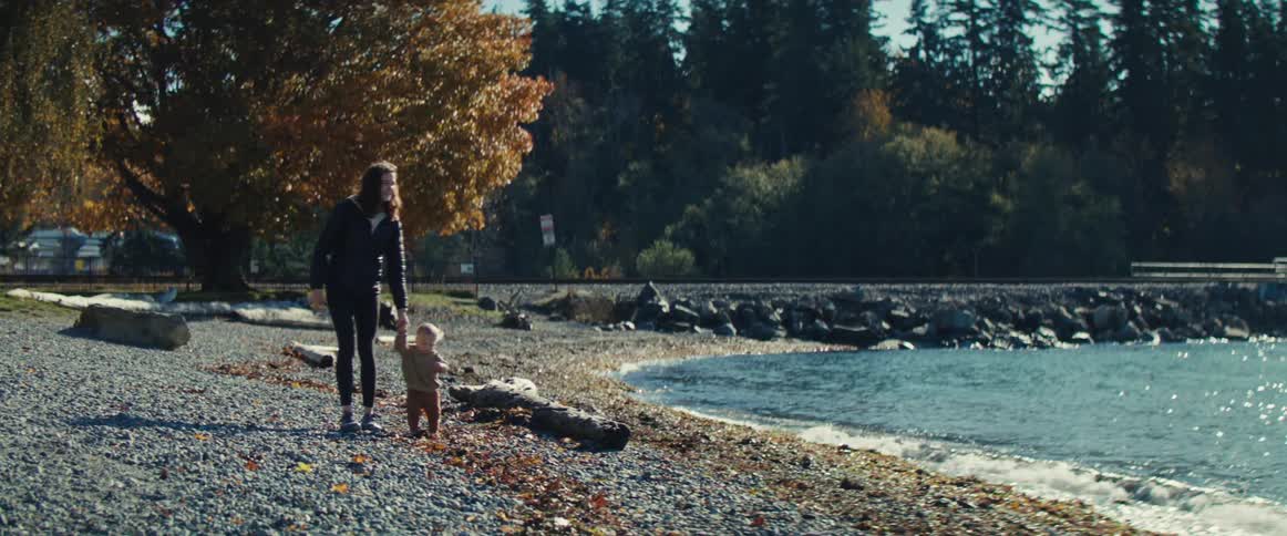Parent walking with a small child along a rocky beach in autumn