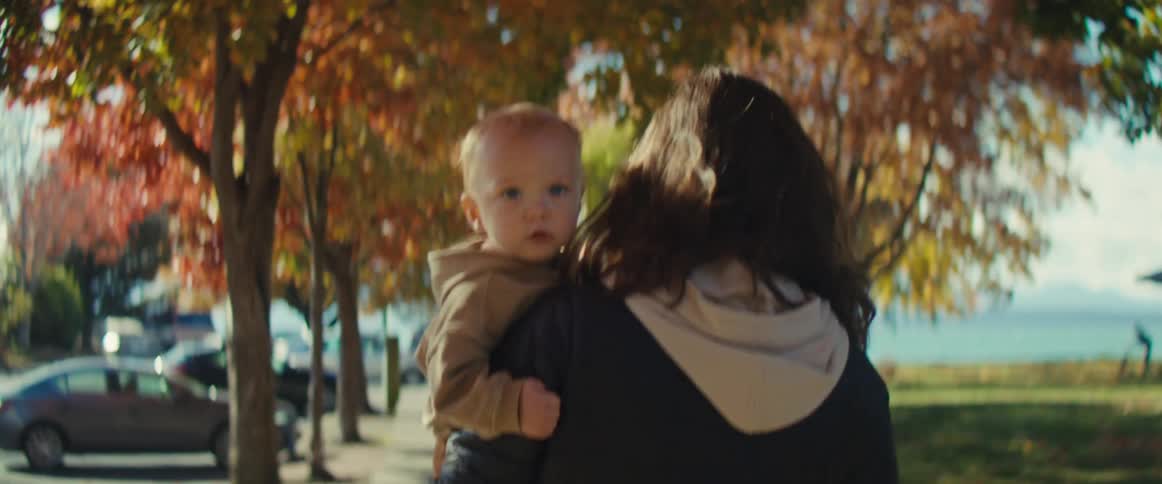 The mother is carrying her son on the sidewalk
