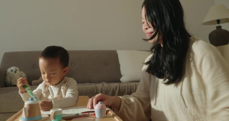 A mother and her son sitting in the living room having fun playing with toys at midday