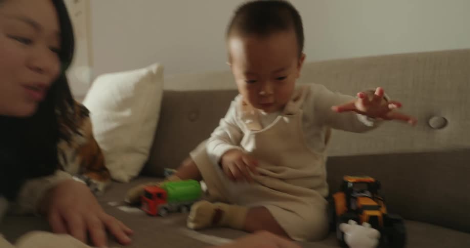 Mother watching her son play with toy cars on the couch