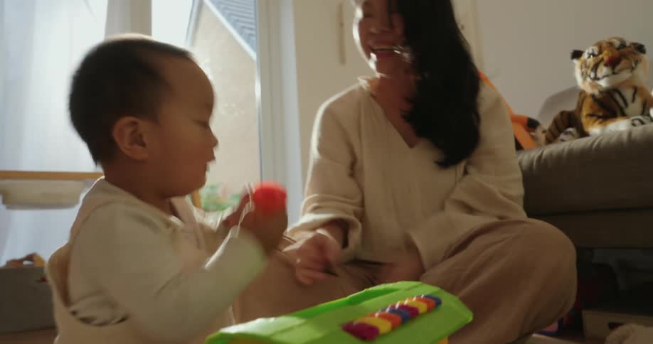 A mother and son play together with colorful toys in a bright living room