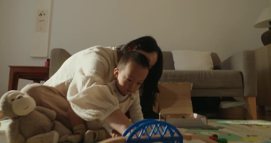 Mother and son assembling toy train tracks on the living room floor