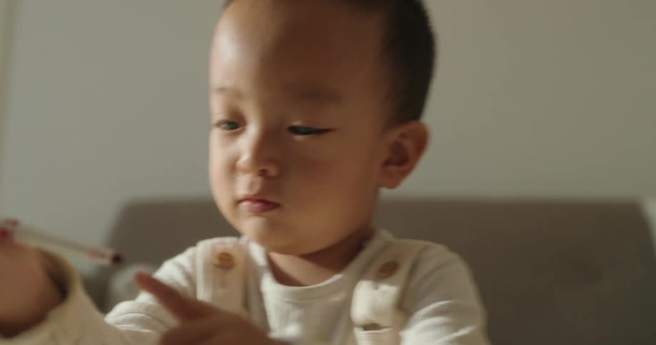 A little boy is in a room playing with a toy that is on a small table in front of him