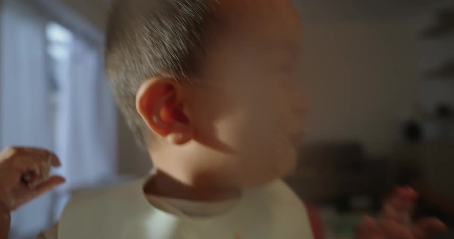 A baby is making a mess and laughing as he eats