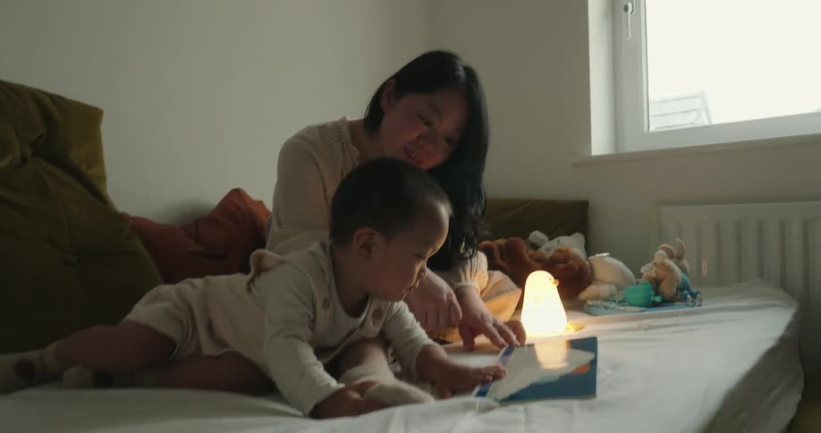 Mother and son read a picture book by a glowing nightlight in the bedroom