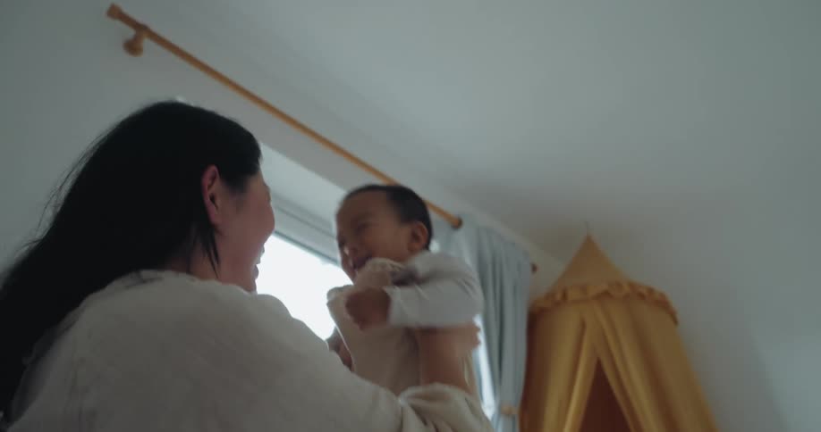 The mother tosses her son up in the air and catches him