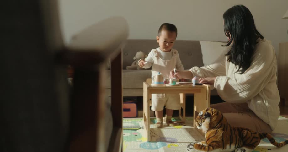 Mother and son playing together at a small wooden table in the living room