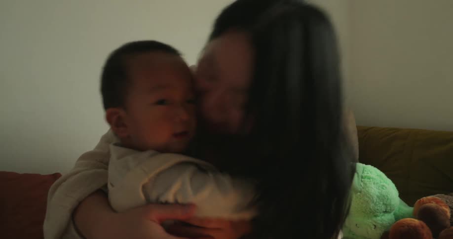 The video features a mother with long dark hair sitting on a couch and lovingly holding a baby dressed in a lightcolored outfitshe hugs the child close and then turns the baby to face her smiling and gently touching them as they interact
