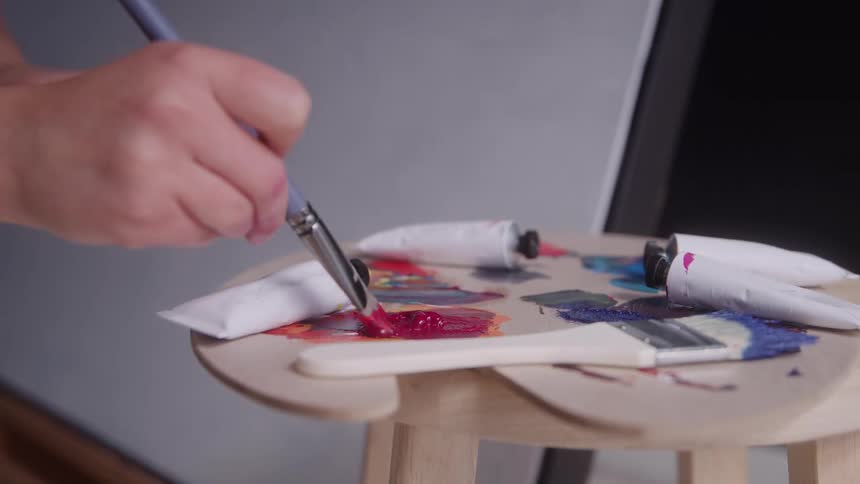 Close up of a young female artist mixing paint on a palette in an art studio