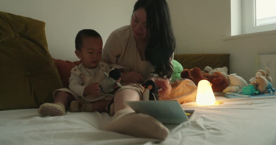 Mother and son playing with stuffed toys in a softly lit room