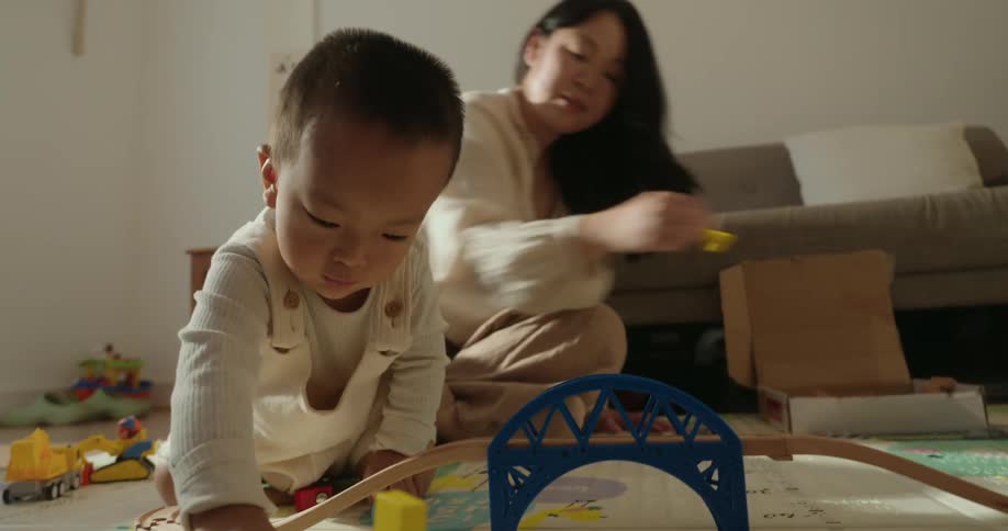 A mother and her young son playing with toys on a play mat