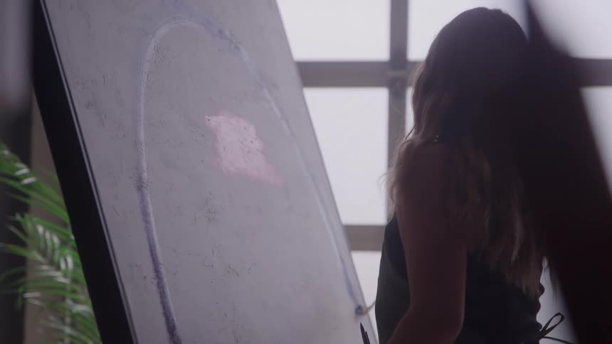 Female artist painting a large canvas in soft natural light