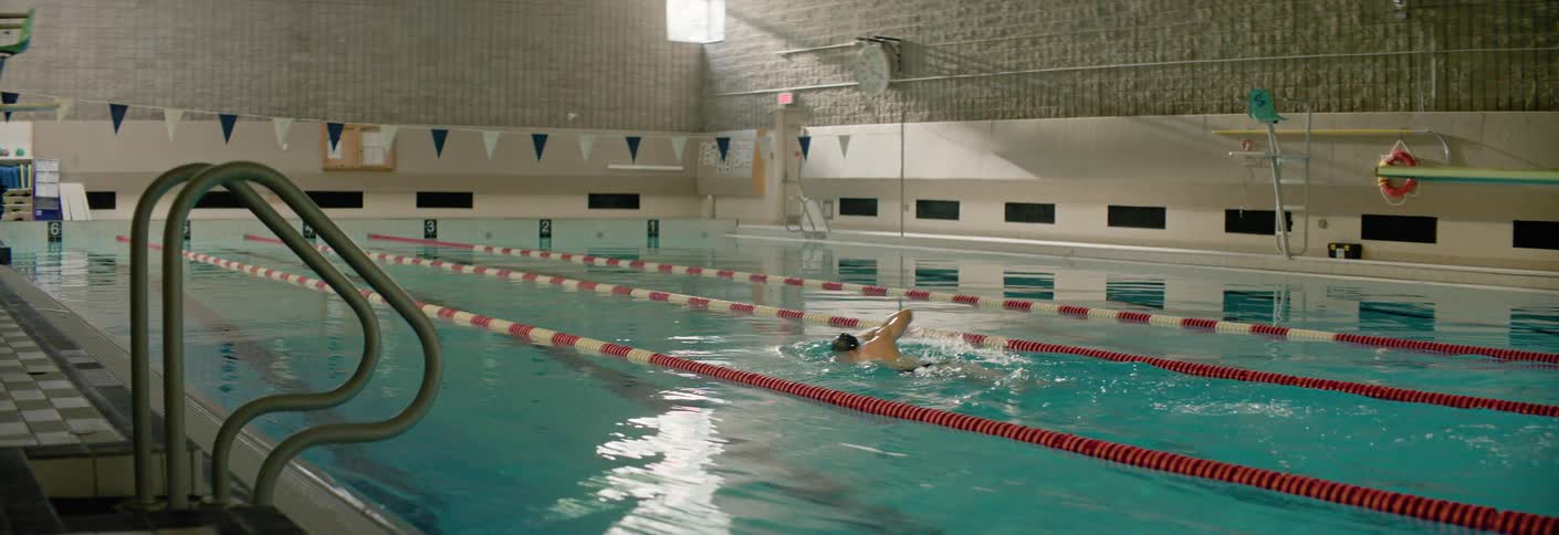 A swimmer practices laps alone in an indoor swimming pool