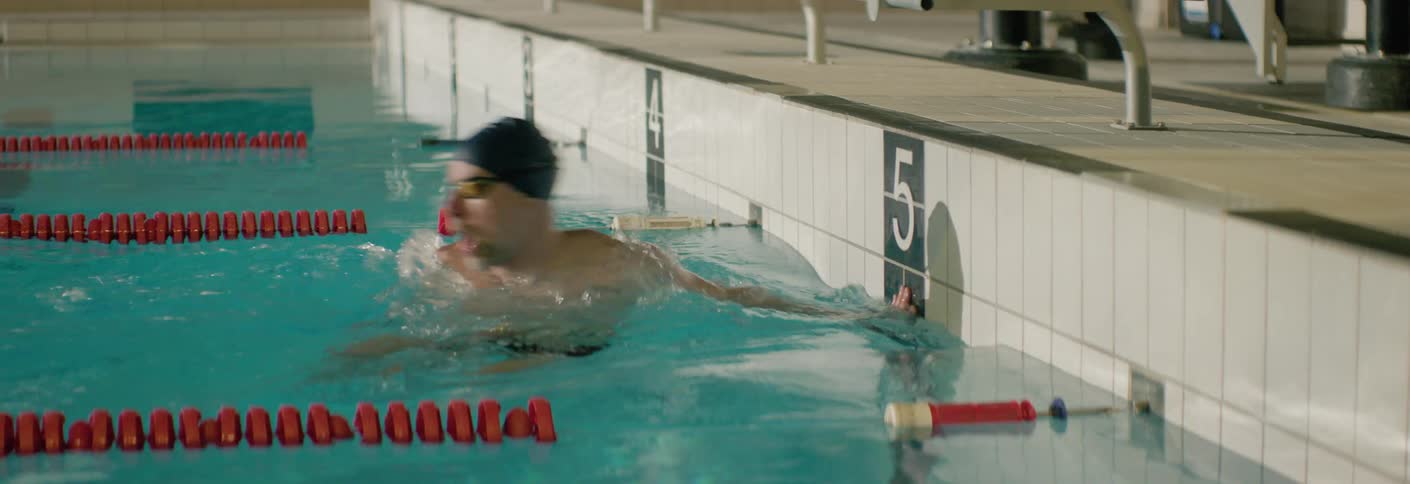Swimmer touches the edge of the pool after completing the leg and turns around