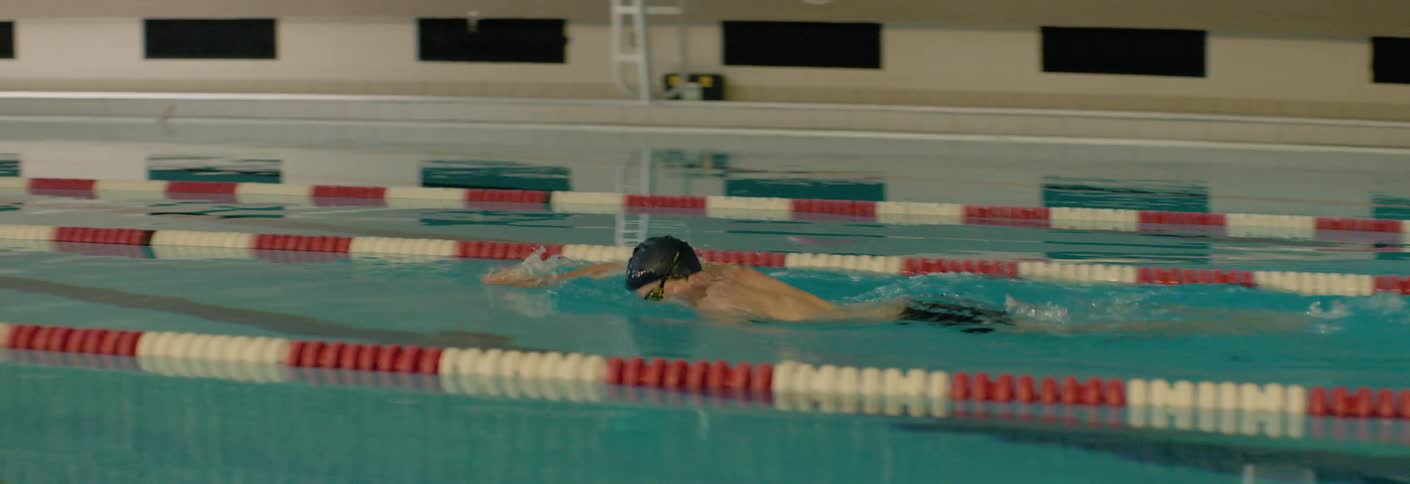 Swimmer swims down a lane in an indoor pool performing the front crawl