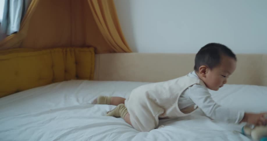Mother playing with her son lying on the bed with a toy