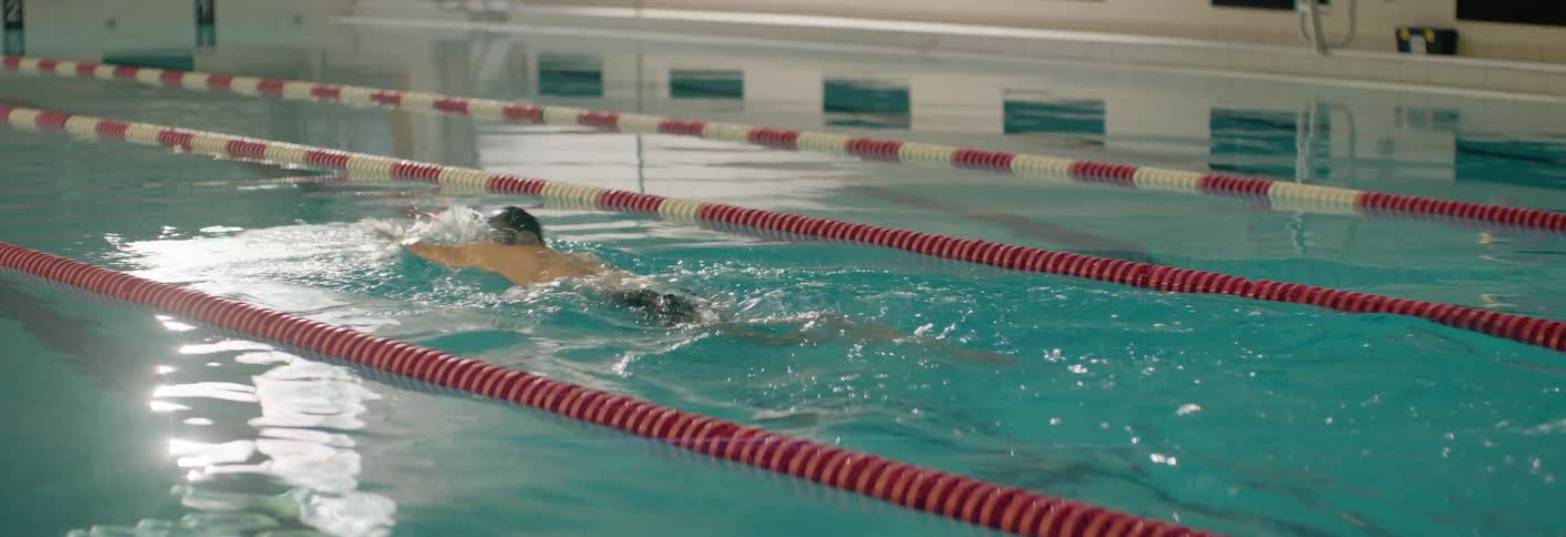 An athlete swims freestyle down a lane in a swimming pool