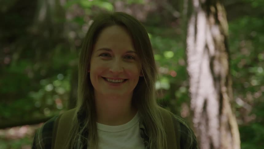 Woman smiling amidst the greenery of a forest