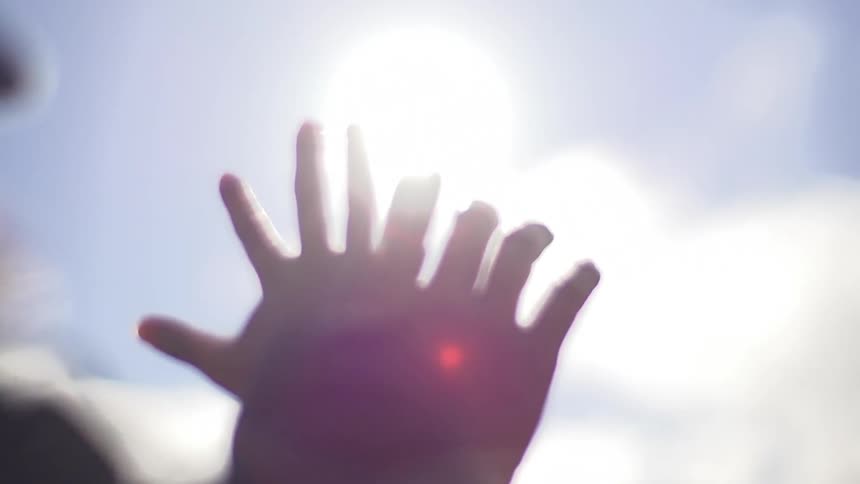 A person puts her hands next to each other in front of the sky