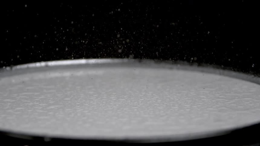 Close up of a person playing a drum covered with white powdered particles