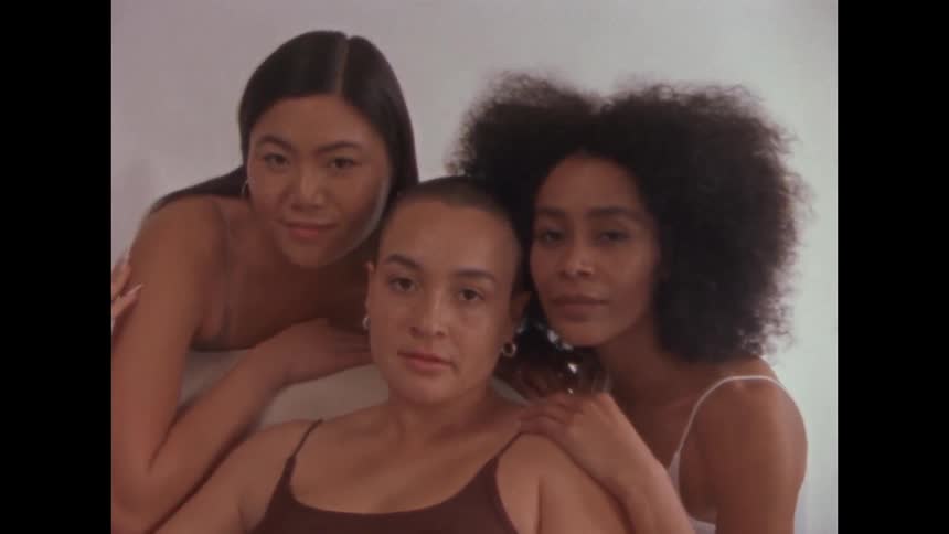 Three people posing together with gentle expressions in a studio