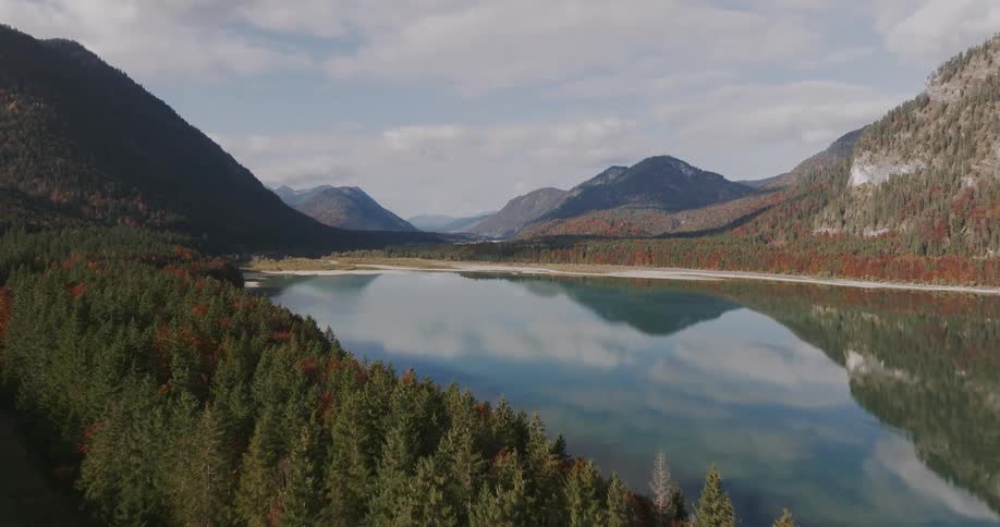 Trees and forested mountains along the coast with mountains across the landscape