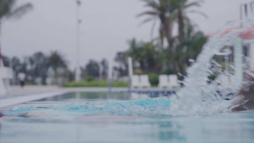 A young black female swimmer swimming in an outdoor pool during daytime