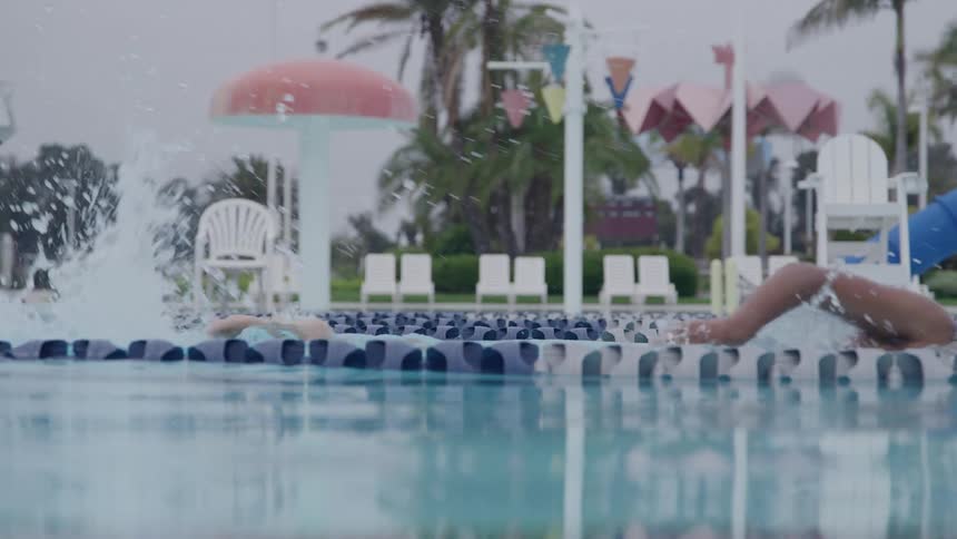 A young man swimming in an outdoor pool during daytime