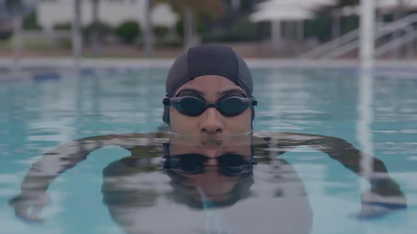 Swimmer wearing a cap and goggles in the pool looking forward