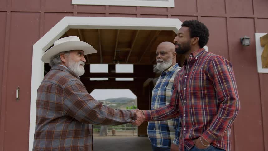 Two men greeting themselves with a handshake while standing outdoors during daytime