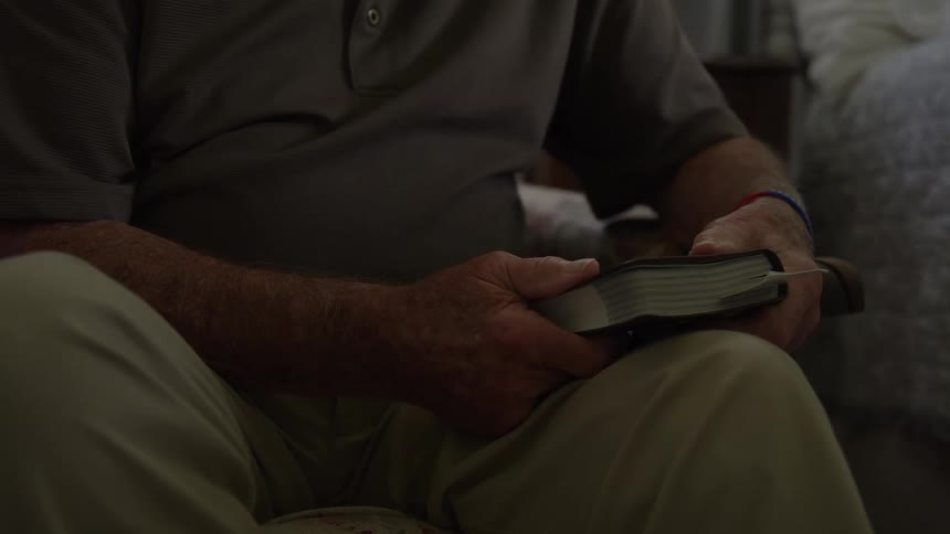 The man is holding a book at home