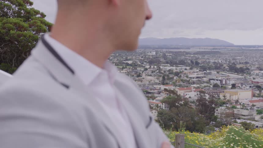 Man in a light suit looking at the city from a viewpoint