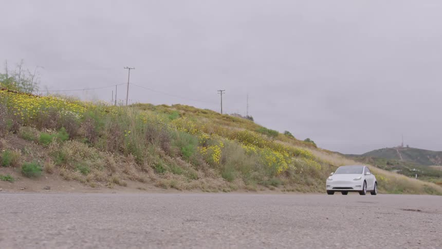 A white car drives down a road