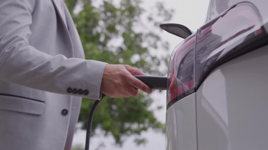 A man plugging a charger into an electric car
